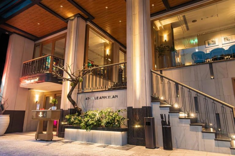 Entrada principal iluminada del La Siesta Premium Saigon Central en Ho Chi Minh, con escaleras y jardines