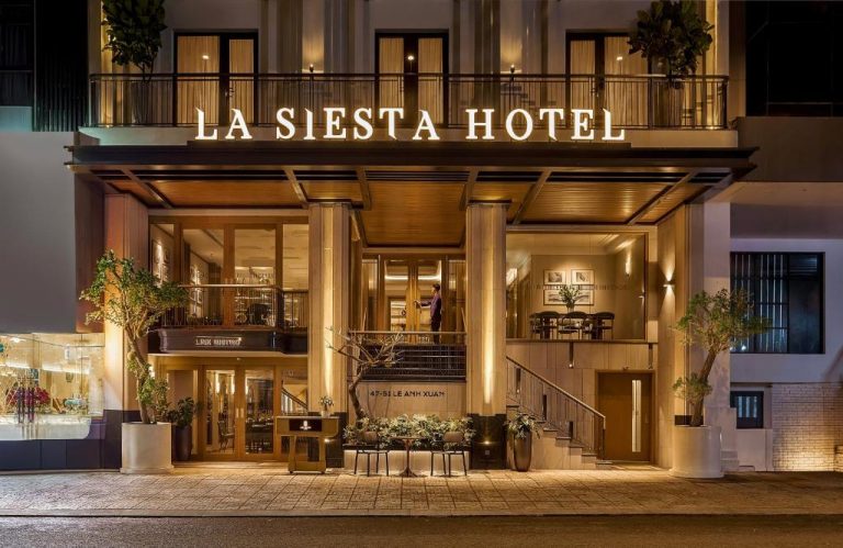 Fachada iluminada de noche con entrada principal del La Siesta Premium Hotel Saigon Central en Ho Chi Minh