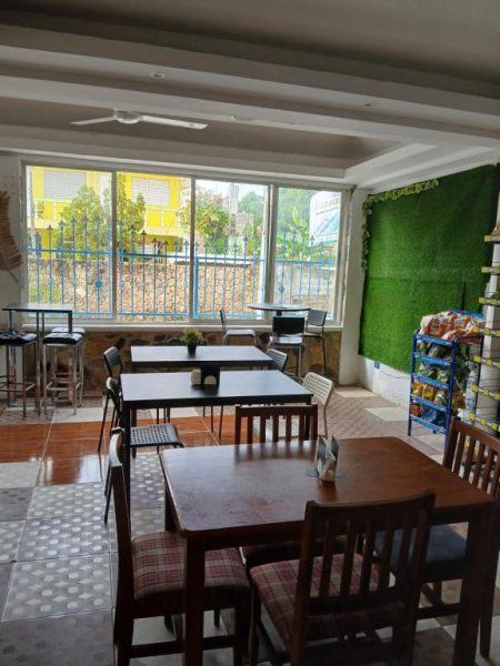 Comedor interior del Hotel Mango con mesas de madera, pared verde decorativa y vistas al exterior