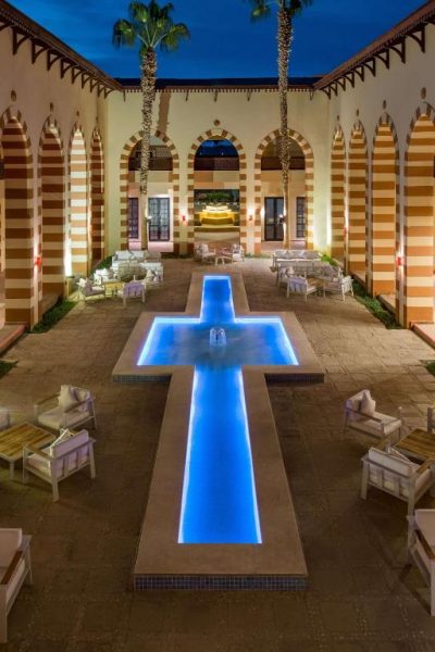 Patio central con fuente en forma de cruz iluminada en azul del Marina Resort Port Ghalib Radisson