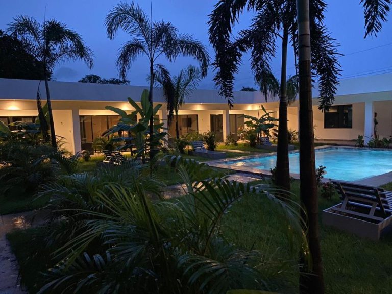 Piscina exterior iluminada de noche rodeada de palmeras tropicales en el Hotel Good Life