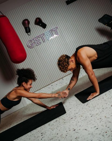 Dos personas entrenando en el gimnasio del hotel NEXT by Savoy Signature con zona de boxeo y yoga