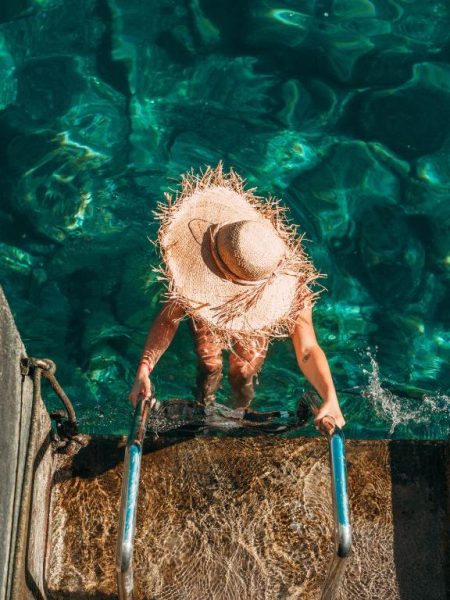 Mujer bajando por escalerilla a la piscina de aguas cristalinas del hotel NEXT by Savoy Signature