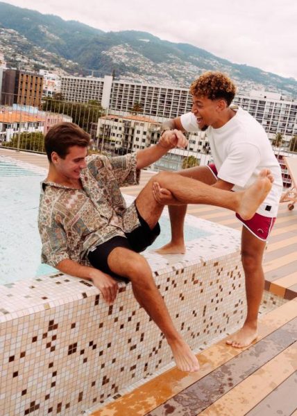 Dos jóvenes disfrutando y riendo junto a la piscina rooftop del hotel NEXT by Savoy Signature