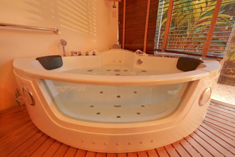 Jacuzzi privado para dos personas con suelo de madera y vistas al jardín en Manary Praia Hotel
