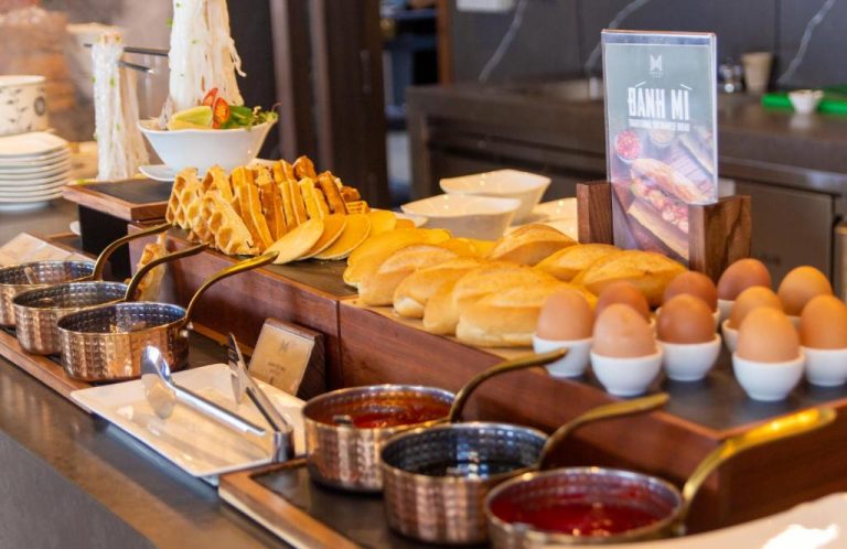 Buffet de desayuno con bánh mì, huevos, waffles y salsas en el M Hotel Danang Vietnam