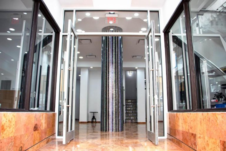 Entrada principal con puertas de cristal y columna decorativa de mosaico del Armas Hotel