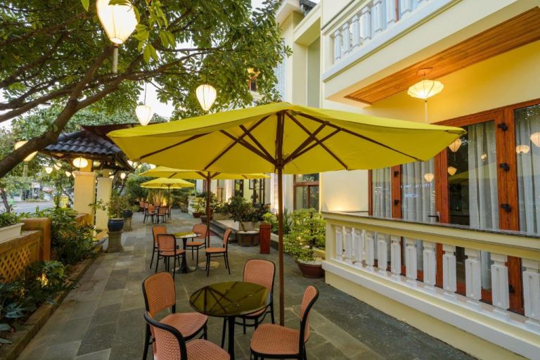 Terraza exterior con sombrillas amarillas y faroles del Ancient Haven Central Boutique Hotel en Hoi An