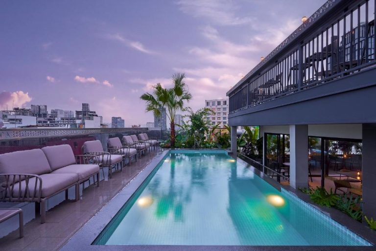 Piscina rooftop iluminada con tumbonas y vistas a la ciudad en La Siesta Premium Saigon Central