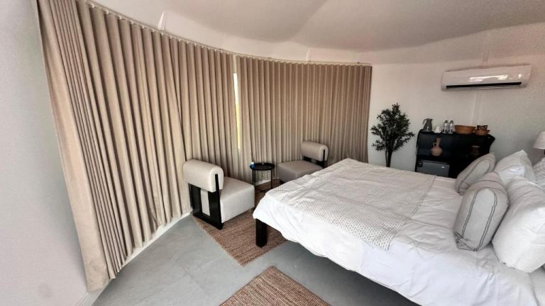 Habitación doble con cama king y cortinas beige en Starry Domes Desert Camp