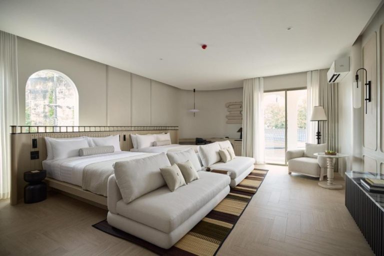 Suite premium con cama king y sofá blanco en el hotel Arco Phuket Town, decoración minimalista elegante