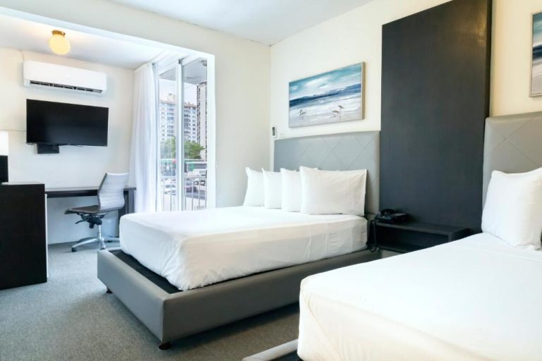 Habitación doble con dos camas y escritorio de trabajo en el Villa Verde Inn con balcón exterior