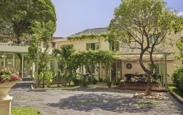 Jardín exterior con árboles y terraza del President Maison Signature by M Village en Vietnam