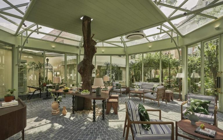 Salón jardín interior con invernadero y árbol central en President Maison Signature by M Village