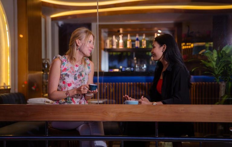 Dos amigas disfrutando de un café en el elegante bar del UMET Seaview Hotel con ambiente moderno