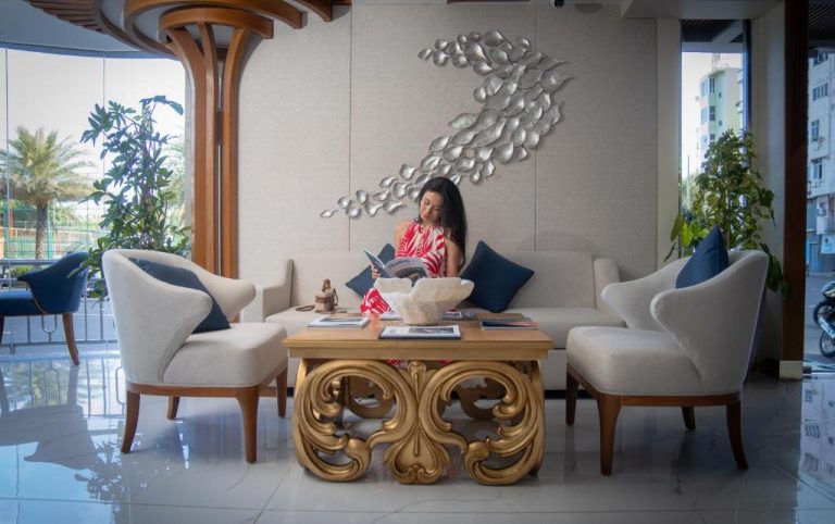 Elegante lobby del UMET Seaview Hotel con sofás blancos, mesa dorada y decoración mural plateada
