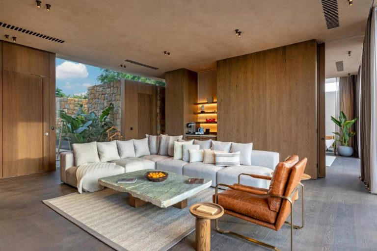 Lujoso salón de suite con sofá blanco, sillón de cuero y pared de madera en Lujo Hotel Bodrum