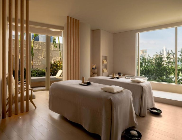 Sala de spa para parejas con dos camillas de masaje y vistas a la ciudad en Dusit Thani Bangkok
