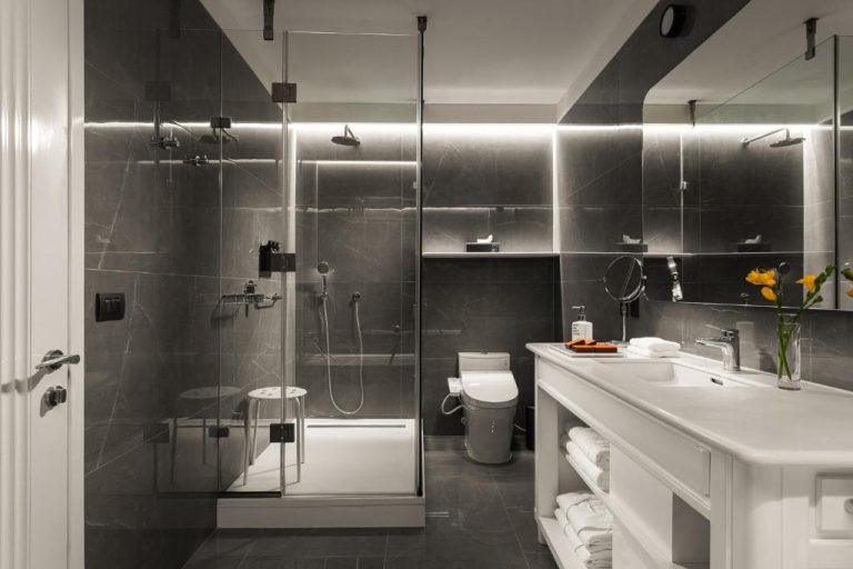 Baño de lujo con ducha de mármol gris y lavabo blanco en Debaines Hotel Santiago