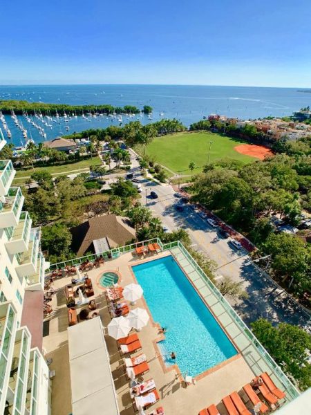 Vista aérea de la piscina exterior con tumbonas y marina del Balcony Ocean View Miami