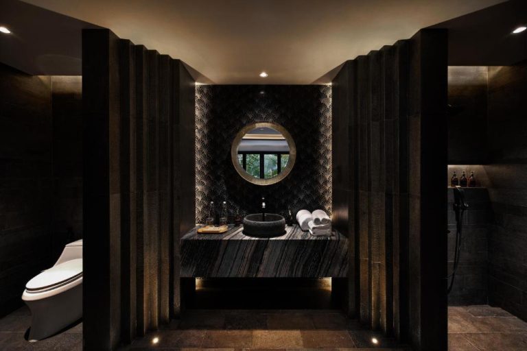 Baño de lujo con mármol negro y espejo circular iluminado en Ayatara Resort Ubud, Bali