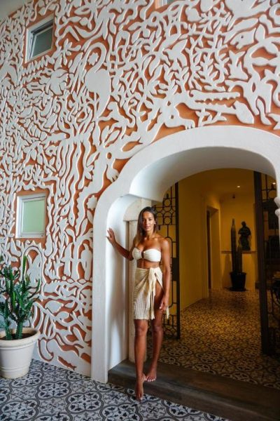 Entrada con arco blanco y pared decorativa del Casa Tortugas Boutique Hotel en Cancún