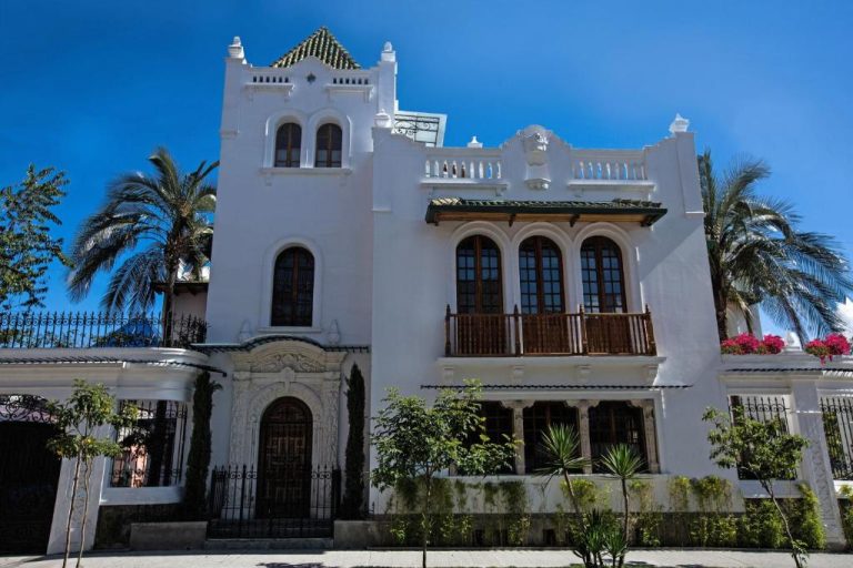 Fachada exterior colonial blanca del Hotel Boutique Cultura Manor by Brater con balcón de madera y palmeras