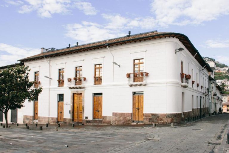 Fachada colonial blanca con puertas de madera del Casa Santa Clara Colonial Boutique Hotel en Quito