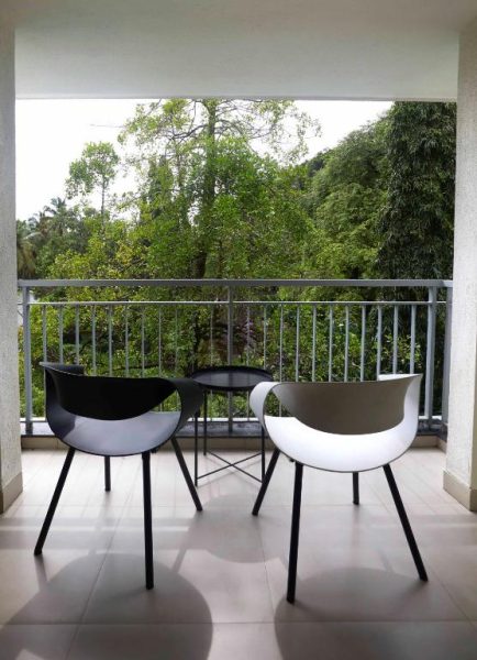 Terraza exterior con sillas modernas en blanco y negro en Radha House Siolim Boutique Hotel con vistas al jardín