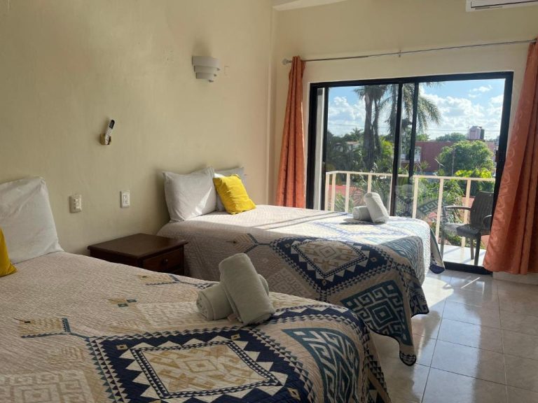 Habitación triple con balcón y vista a palmeras tropicales en Hotel Caribe
