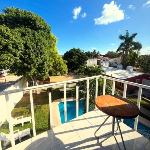 Vista desde el balcón del Hotel Caribe con piscina, jardín tropical y palmeras bajo cielo azul