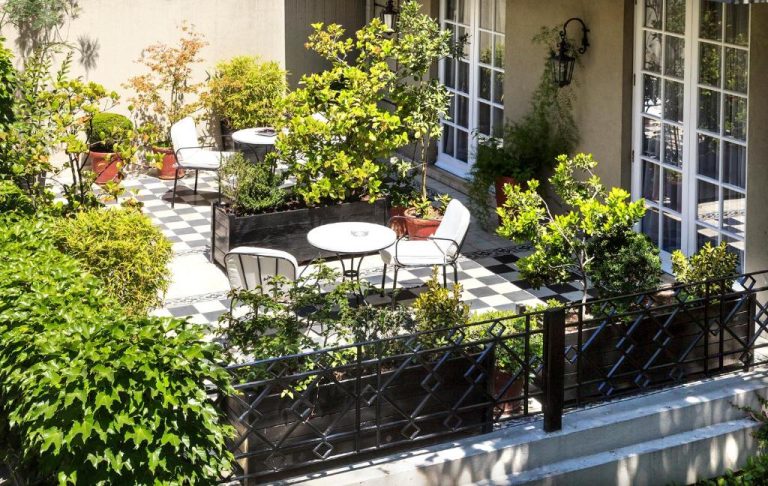Terraza ajardinada con suelo de ajedrez y mobiliario blanco del Hotel Boutique Le Reve