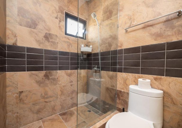 Baño con ducha de cristal y azulejos de mármol en Hotel La Casona MC