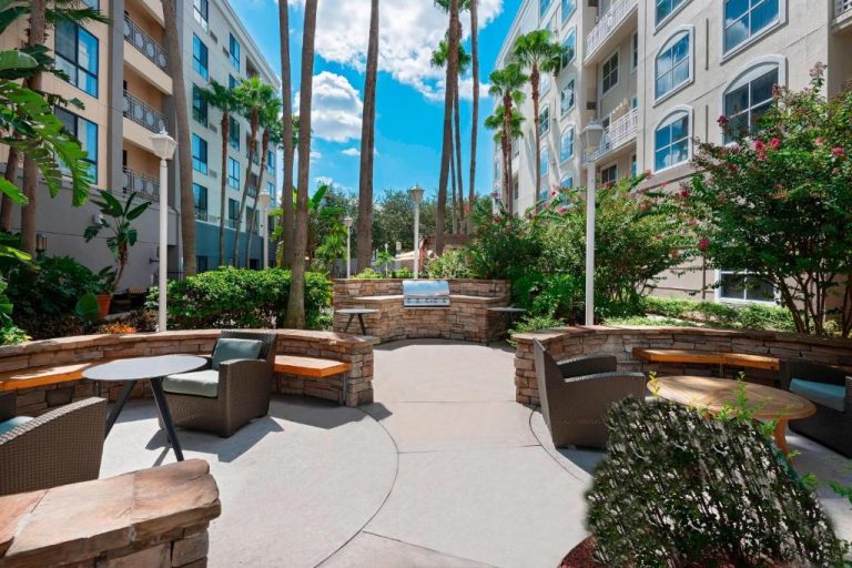 Patio exterior con zona de barbacoa y área de descanso del Residence Inn Tampa Downtown rodeado de palmeras