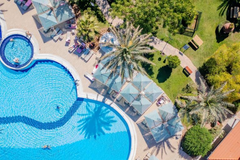 Vista aérea de la piscina exterior con hamacas y palmeras del Belconti Resort Hotel