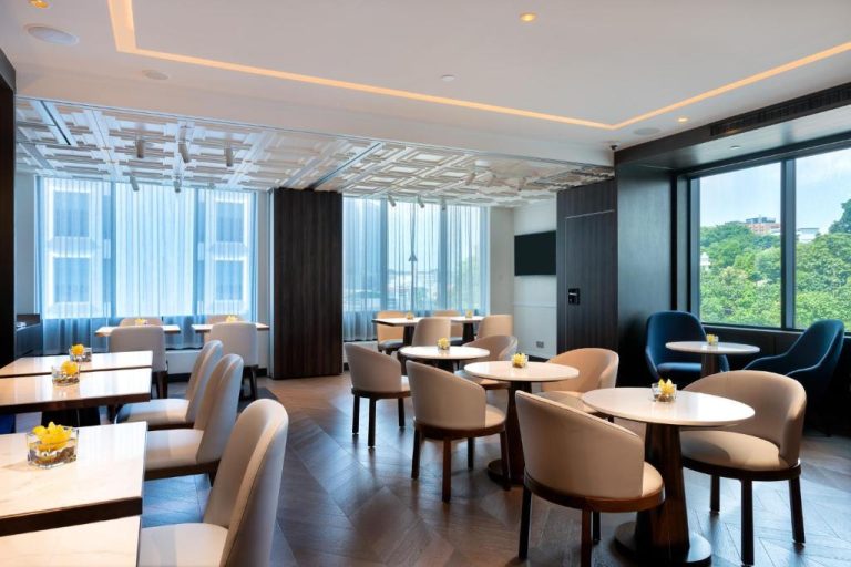 Elegante restaurante del Grand Park City Hall con mesas blancas, sillas beige y vistas al exterior