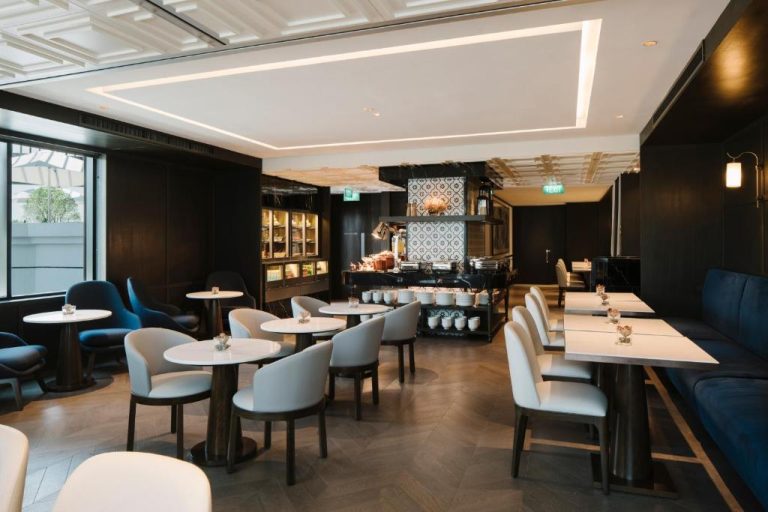 Elegante restaurante buffet interior del Grand Park City Hall con mesas blancas y sillas grises