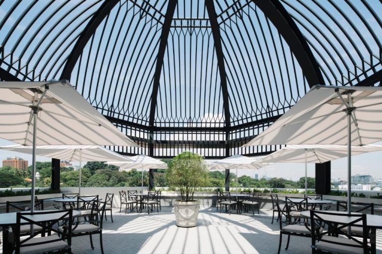 Terraza exterior con cúpula metálica y mesas del restaurante del Grand Park City Hall en Singapur