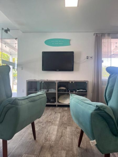 Sala de estar con sillones turquesa y televisor en pared del Dona Catarina Hotel