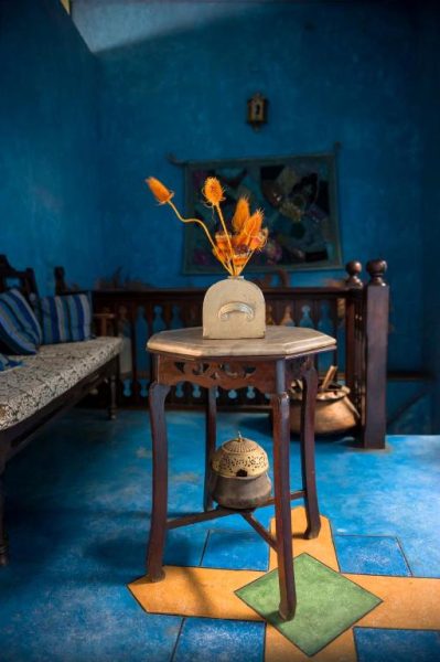 Salón con decoración azul y mesa de madera vintage con flores secas en Shaba Boutique Hotel