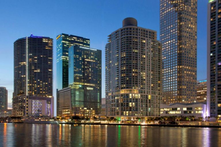 Vista nocturna del JW Marriott Marquis Miami con skyline iluminado y reflejo en la bahía de Biscayne
