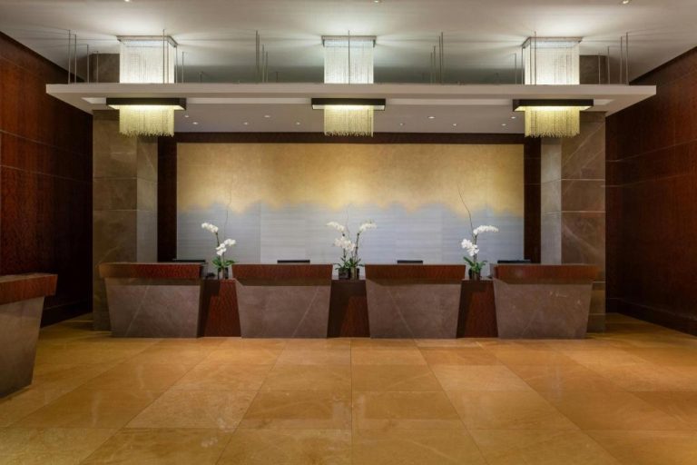 Recepción principal del JW Marriott Marquis Miami con elegantes mostradores de mármol y orquídeas blancas