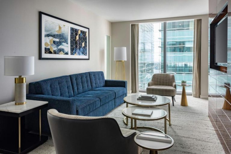 Sala de estar de suite con sofá azul y vistas al skyline en JW Marriott Marquis Miami