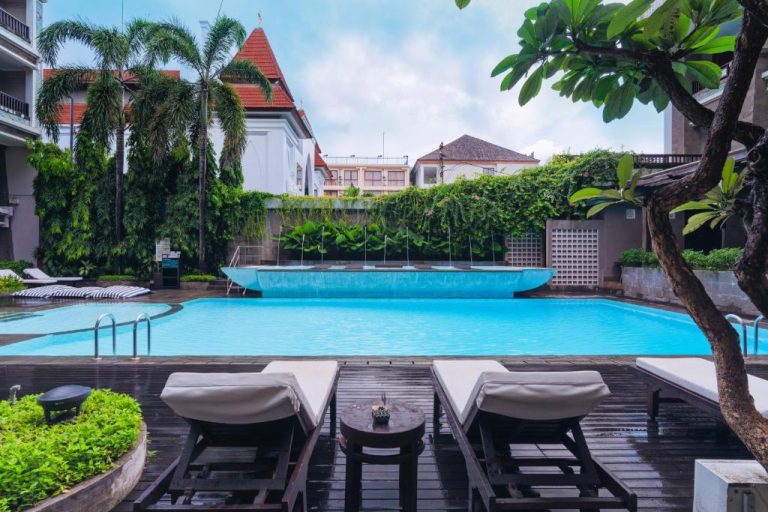 Piscina exterior con tumbonas y jardín tropical en The Vira Bali Boutique Hotel & Suite