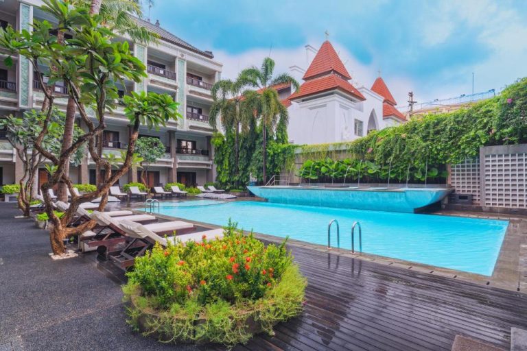 Piscina exterior con tumbonas y jardines tropicales del The Vira Bali Boutique Hotel & Suite en Bali
