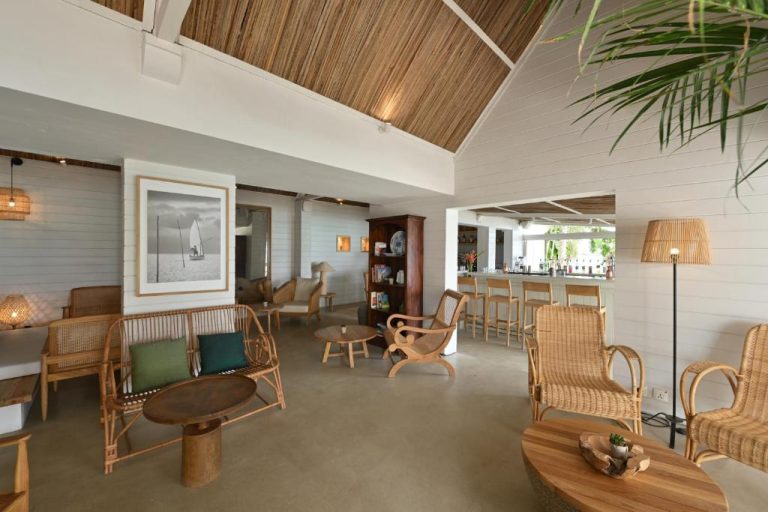 Lobby y bar con mobiliario de ratán y techo de paja del Veranda Grand Baie Hotel & Spa