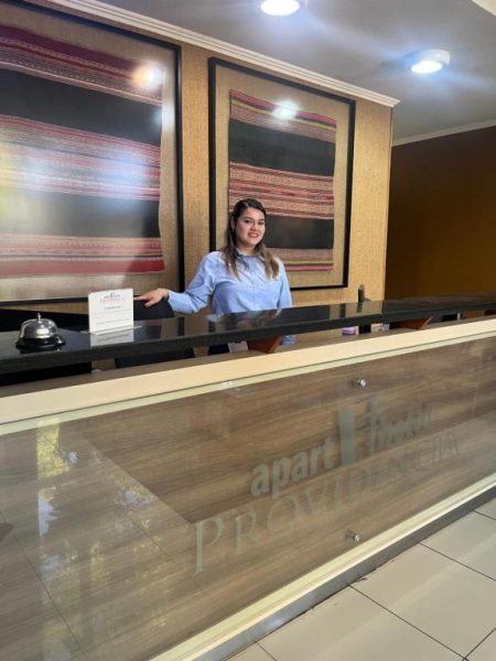 Recepcionista sonriente en el mostrador de recepción del Apart Hotel Providencia