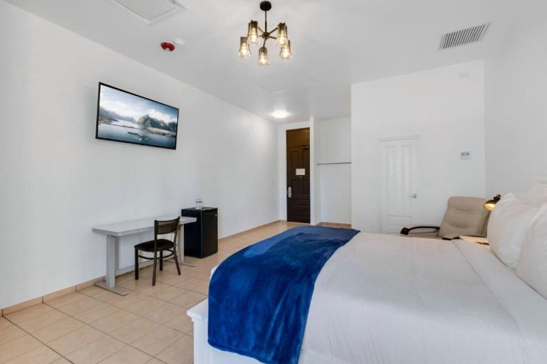 Habitación doble con cama king size y TV de pared en Armas Hotel, decoración blanca moderna