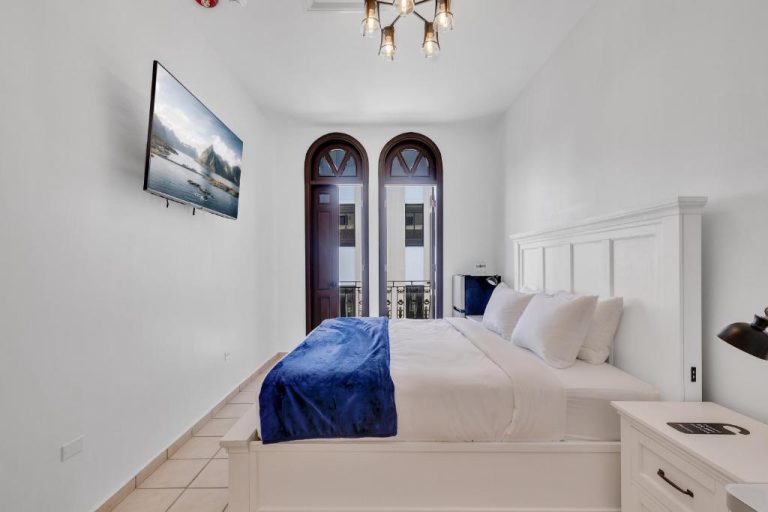 Habitación doble con cama king, balcón con puertas arqueadas y TV en Armas Hotel