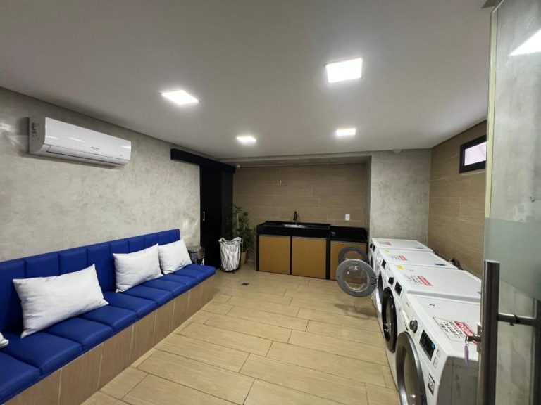 Lavandería común con lavadoras, sofá azul y aire acondicionado en Flat Ramad